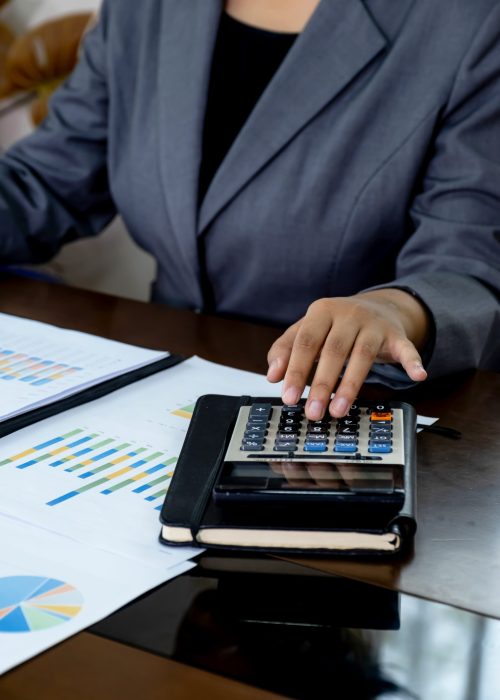 Businesswomen bookkeeper hand use calculator analysis the graph for Setting challenging business goals and ready to achieve target at home office.