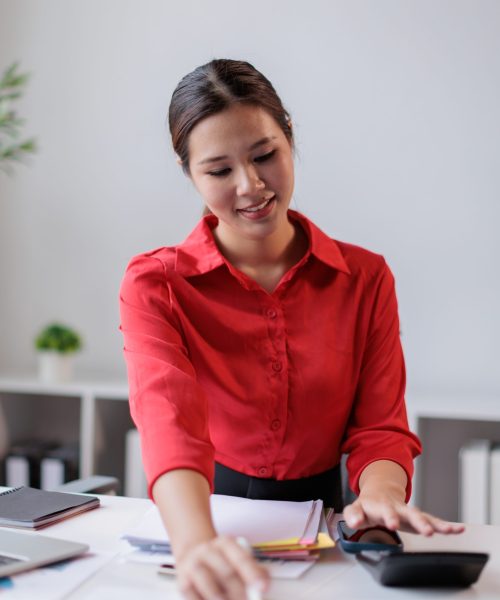 Asian businesswoman managing business finances, calculating company budget, analyzing market data, and working on financial reports in a modern office environment
